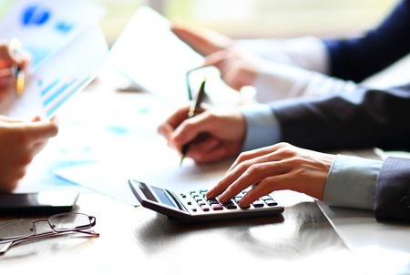 Business people counting on calculator sitting at the table Close up of hands and stationery