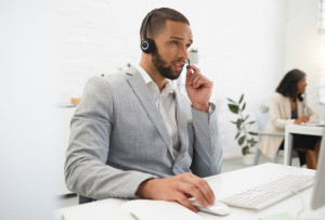 Advisor, computer and businessman in call center talking for loan advice, online help and consulting. Mic headset, finance consultant or agent typing on live chat for insurance service, CRM support