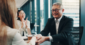 Cooperation, handshake and business people in meeting, teamwork and promotion with bonus. Japan, group and employees with celebration, collaboration and partnership with success, deal or negotiation