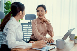 Two young businesswoman work together in office workspace. Enthusiastic